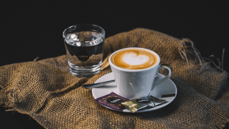 Kaffeespezialität Wiener Melange mit Zucker und einem Karamell Gebäck in Bio-Qualität von fabia und ein Glas Wasser